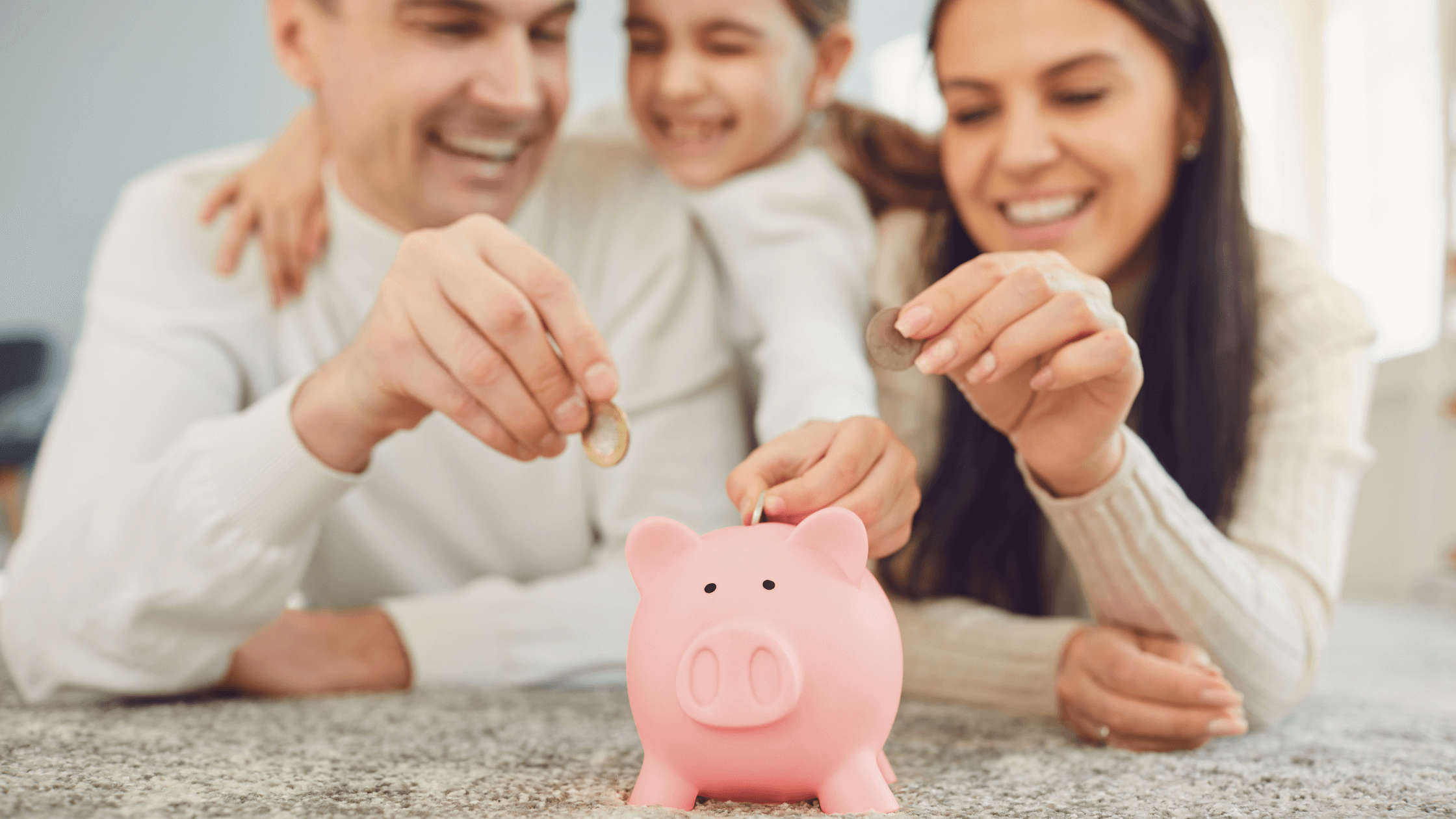 Família sorrindo enquanto deposita moedas em um cofrinho rosa, representando o planejamento financeiro e a importância da Previdência Privada para garantir o futuro.